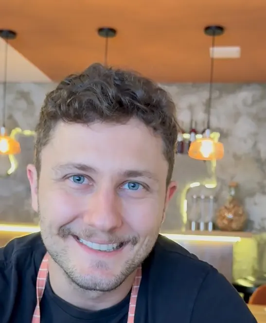 O chef do Cottura sorrindo, de avental listrado coral e branco