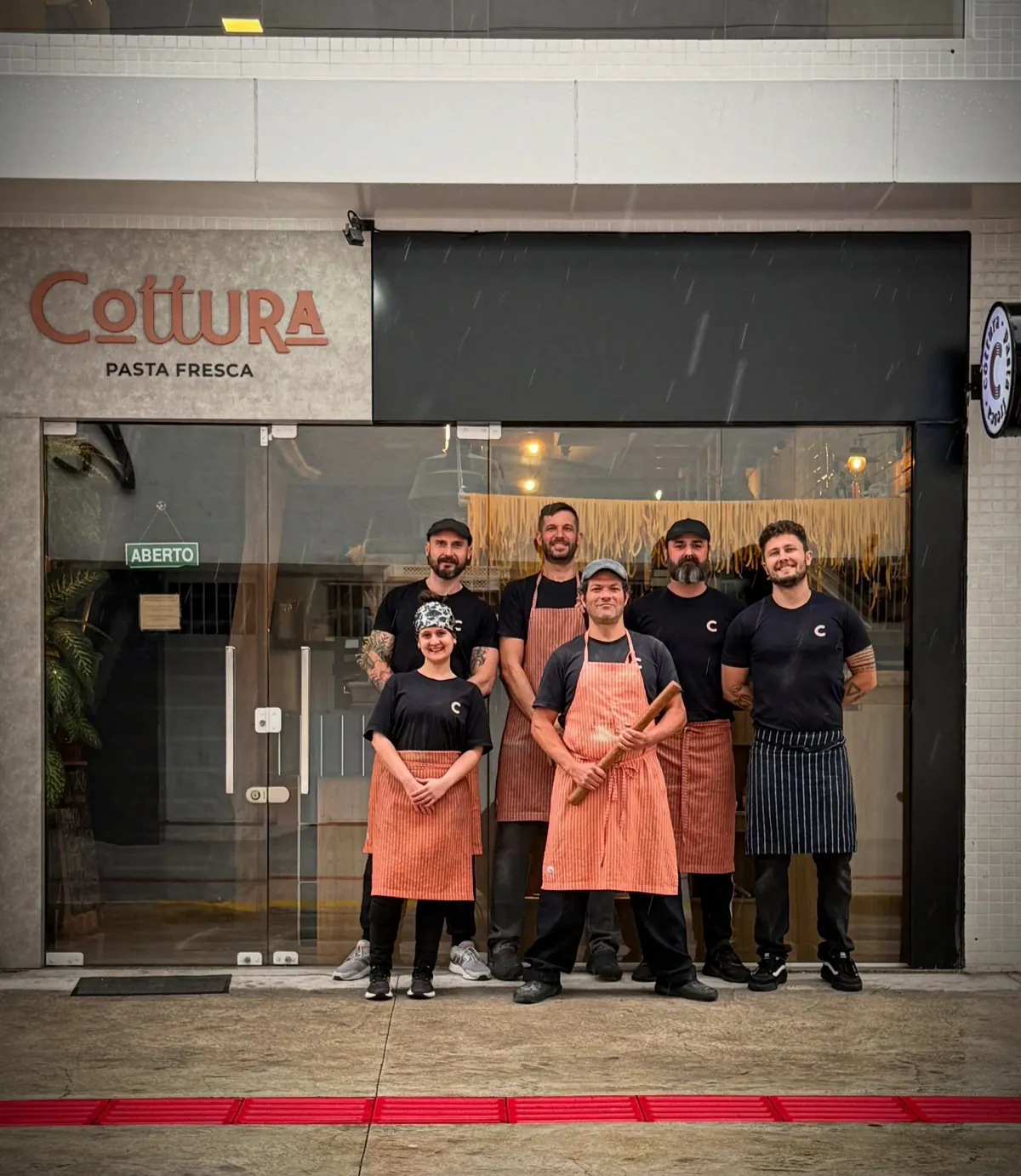 A fachada do Cottura com a equipe de avental listrado na porta