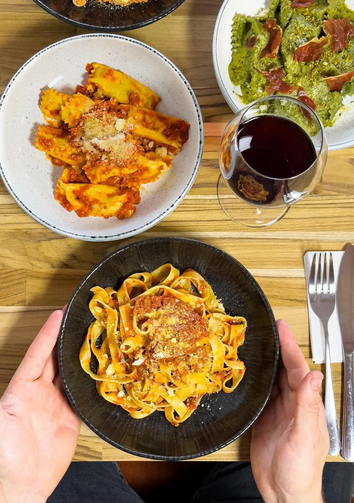 Pratos de massa e uma taça de vinho numa mesa do Cottura